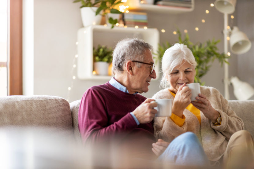 Elderly couple drinking coffee together on the sofa at home